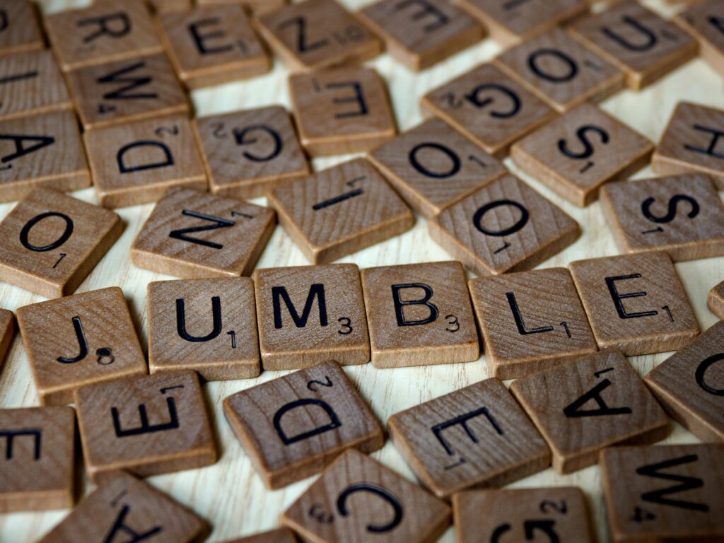 Close-up of scattered Scrabble tiles forming the word 'jumble' on a wooden surface.